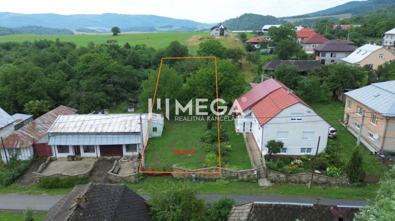 A plot of land in Oľšinkov suitable for living, surrounded by greenery and nearby houses.