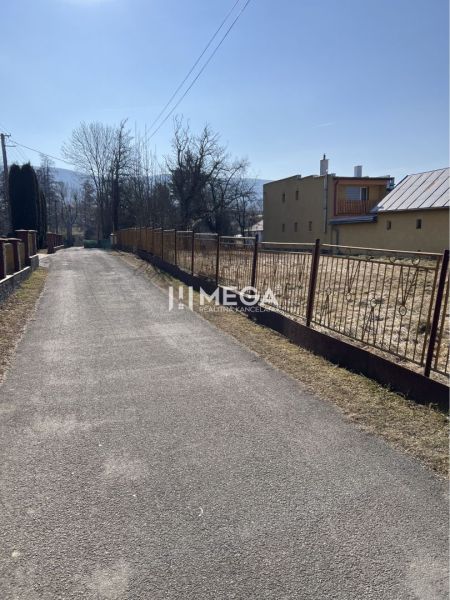 The road by the residential plots in Modra nad Cirochou, surrounding houses and greenery.