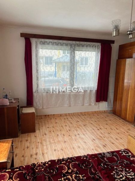A room in a family house with a wooden decor floor, red curtains, and cabinets.