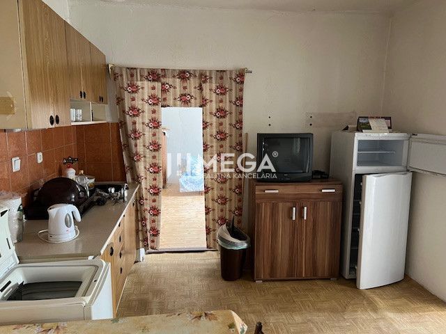 A kitchen in a family house with a wooden decor floor, containing older furniture.