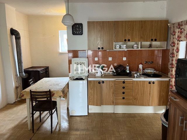 A kitchen in a family house with a wooden decor floor and older furniture.