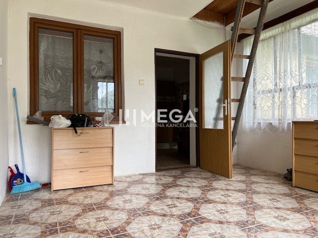 A room in a family house with a ceramic floor and stairs, wooden doors and windows.