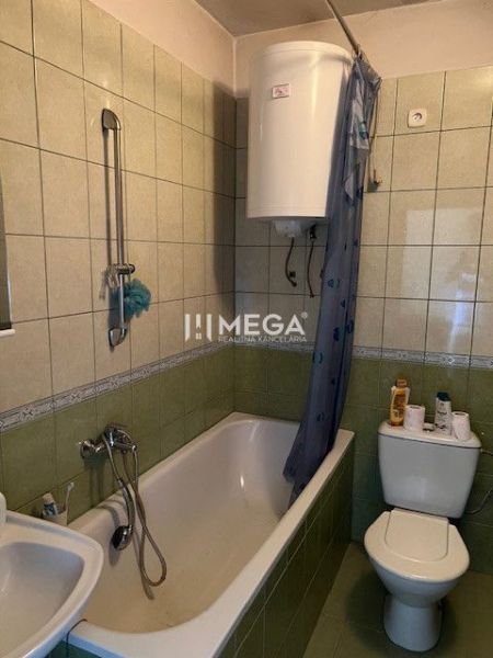 A bathroom with a bathtub and toilet tiled with green tiles in a family house.