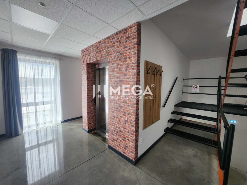 A hallway in an office with an elevator, staircase, and a hanging wall with hooks.