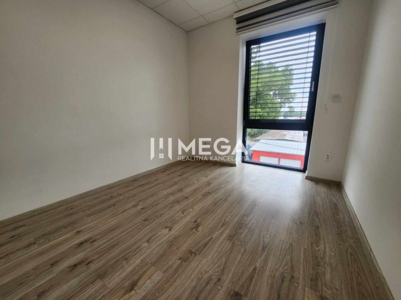 An office with a wood-patterned floor and a large window, simple interior.
