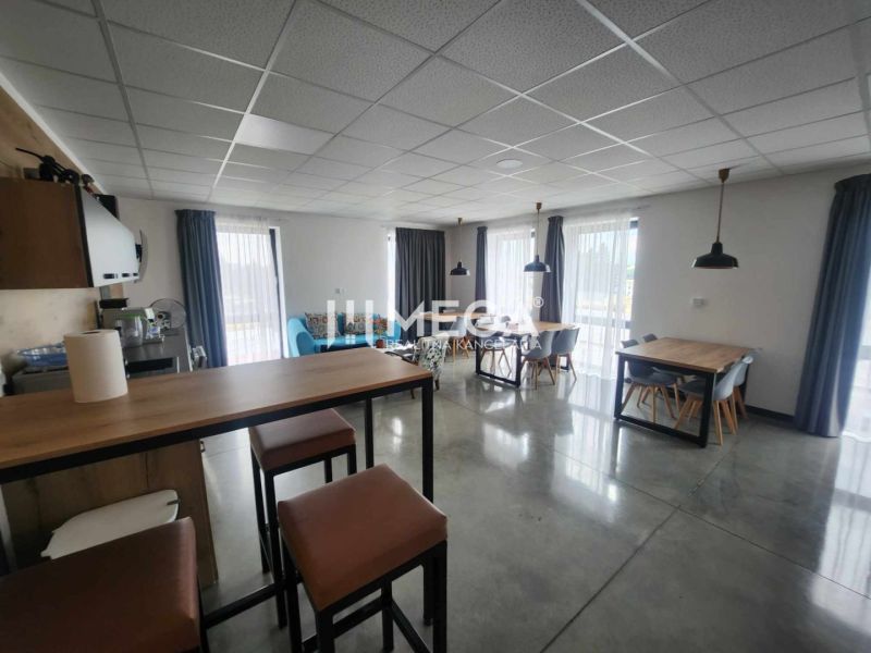 A well-lit office with a concrete floor, equipped with desks and chairs.