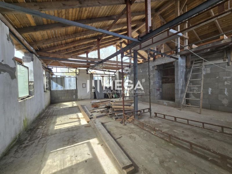 The interior of an unfinished family house with exposed wooden roof structure and unplastered walls.
