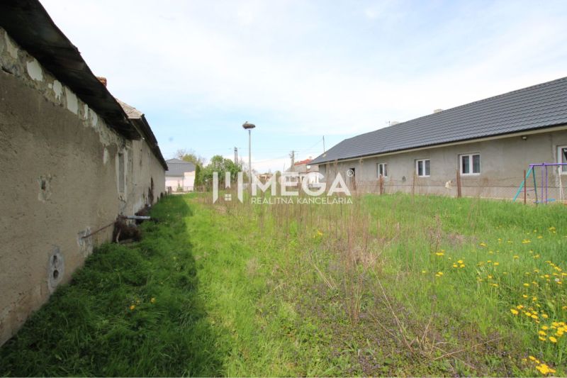 Residential plots in Senné with a dilapidated building and grassy area.