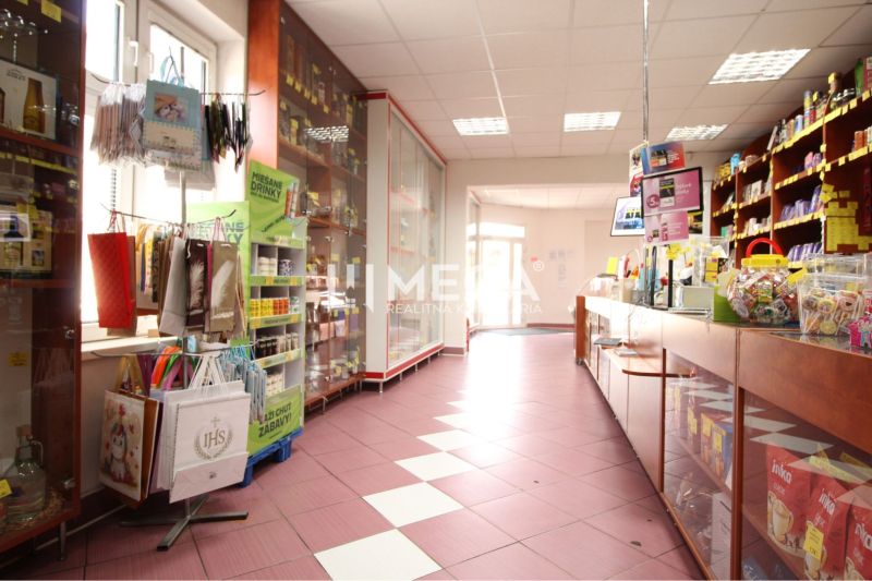 Retail space with shelves and goods, floor with wooden decor, strong lighting.