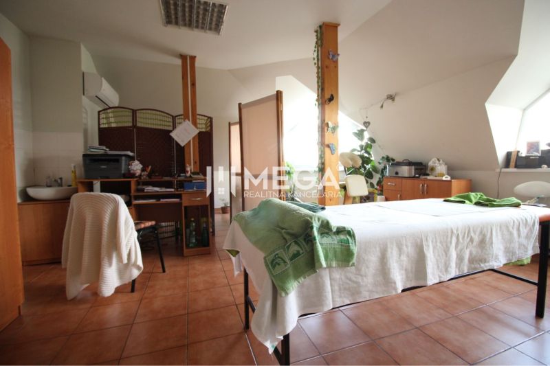 Massage room with a bed and an office desk, floor with wooden decor.