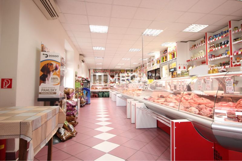 Interior of a commercial space with meat products, shelves, wooden decor flooring.