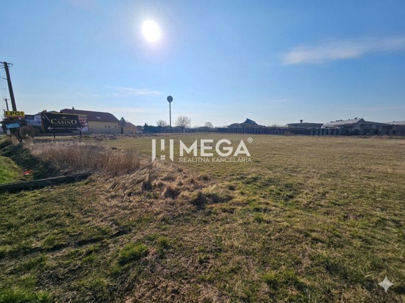 Production facilities in Hriadky, grassy area and buildings with a clear sky.