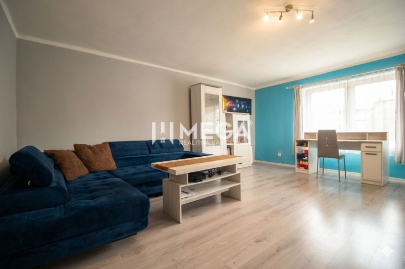 Living room with a blue sofa, table, and wooden decor flooring in a family house.