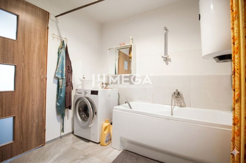 A bathroom in a family house with a washing machine, bathtub, mirror, and curtain.