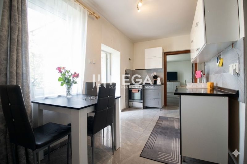A kitchen in a family house with a dining table, flowers, and appliances.