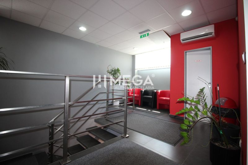 The staircase leading to the offices, with plants and red chairs in the interior.