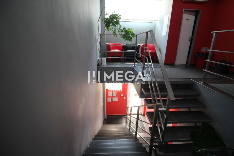 A hallway in offices with a metal railing and a red chair.