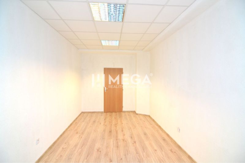 An office with a wooden floor, white walls, and ceiling lighting.