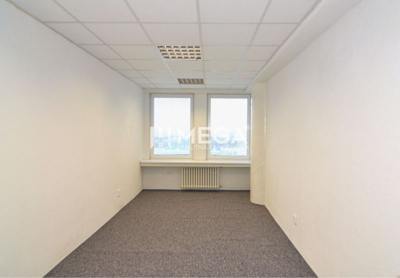 Interior of an office with white walls, carpet, and two windows.
