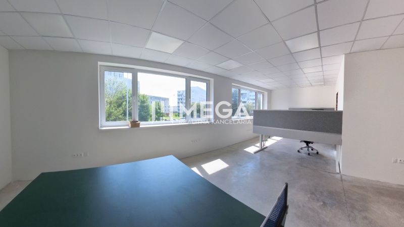 Bright office spaces with large windows and concrete flooring.