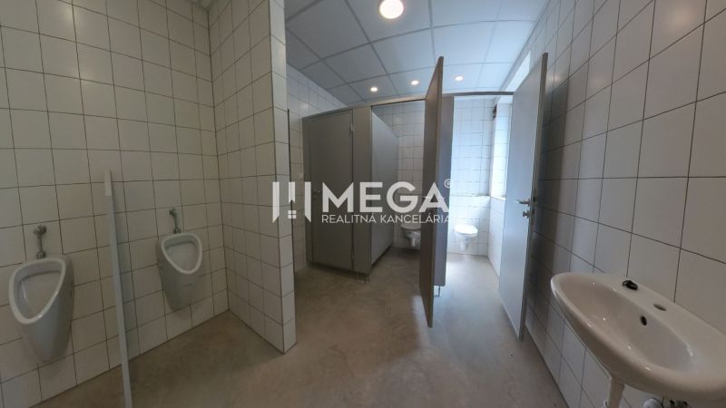 In the offices, there are toilets with white tiles and several stalls.