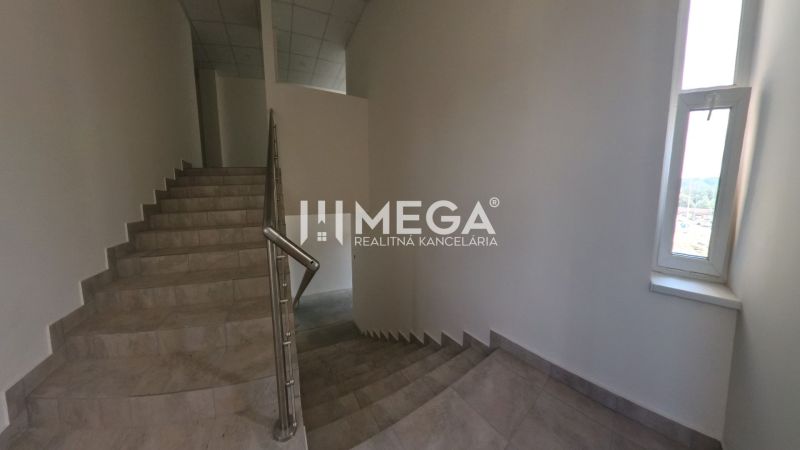 A staircase in offices with a tiled floor and a window providing natural light.