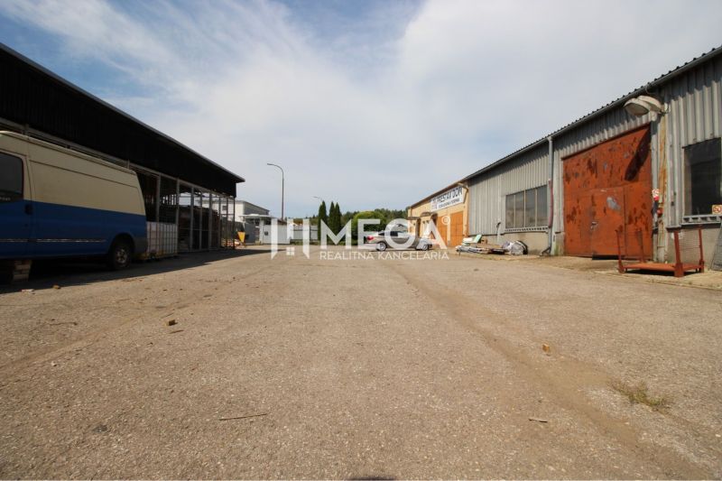 The exterior of warehouses and halls on Fidlikova Street in Humenné with parked vehicles.