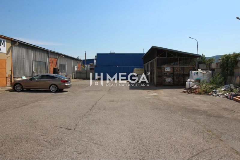 An area of warehouses and halls in Humenné on Fidlikova Street with a parked car.
