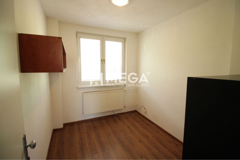 A room in an office with a wood-patterned floor, white walls, and a wall cabinet.