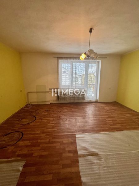A room in a family house with a wooden decor floor and a yellow wall.