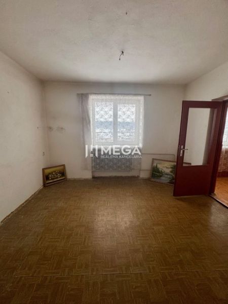 A room in a family house with a wooden decor floor and paintings leaning against the wall.