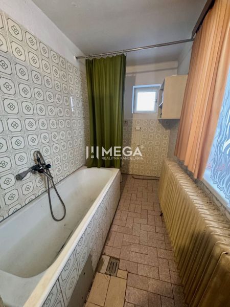 A bathroom in a family house with a bathtub and decorated tiles.