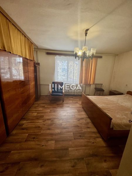 Bedroom in a family house with wood-patterned flooring, chandelier, and wardrobe.
