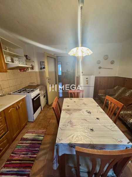 A kitchen in a family house with wooden decor, a dining table, a stove, and a refrigerator.