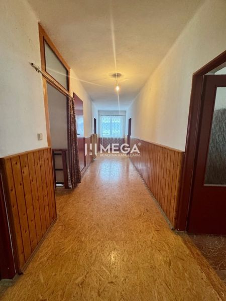 A hallway with a panel wall and a wooden decor floor in a family house.