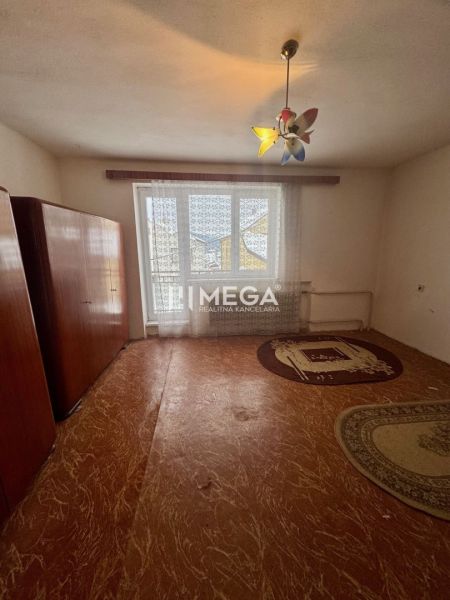 Interior of a family house with possibly an older carpet, wardrobes, and a window with a curtain.