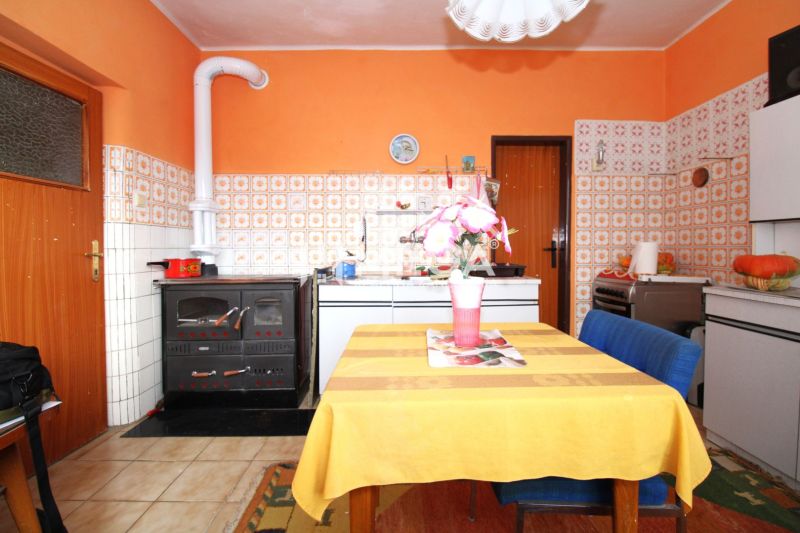 A kitchen in a family house with orange walls, tiles, and a dining table.