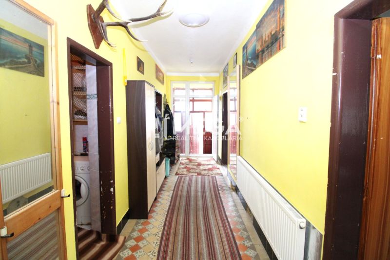 A hallway in a family house with a radiator, carpets, and wall decorations.