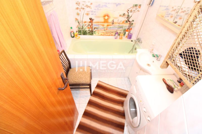 A bathroom in a family house with a green bathtub, a washing machine, and decorative tiles.