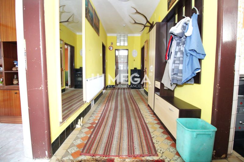 A hallway in a family house with yellow walls, a large mirror, and a long rug.
