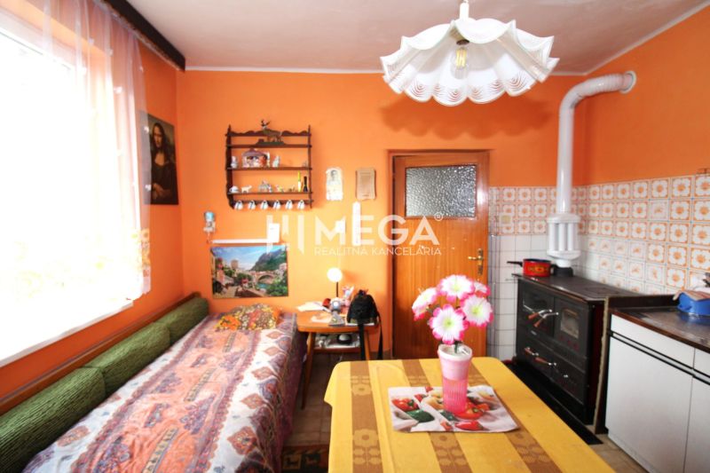 A kitchen in a family house with orange walls, a stove, and a floral decoration on the table.