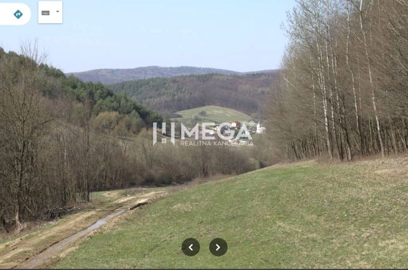 The landscape of Maškovce with agricultural and forest lands surrounded by hills and forests.