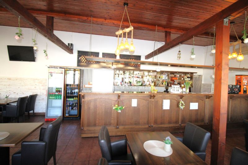 Gastro premises with a wooden bar and ceiling, floor with wooden decor, flowers on the tables.