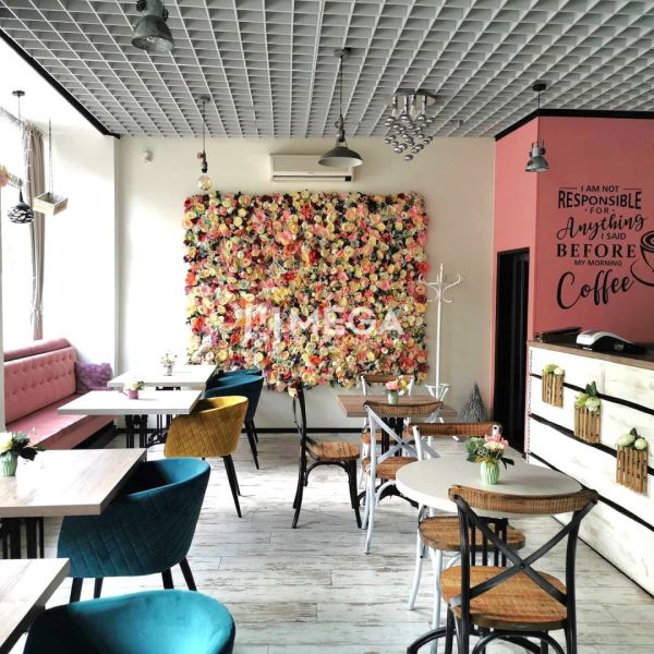 A café with a flower wall in the dining area and chairs of various colors.