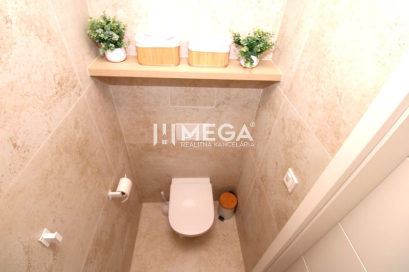 A toilet with marble tiles and decorative plants in a 3-room apartment.