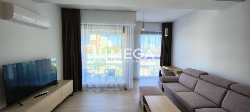 A living room in a three-room apartment with a comfortable sofa and large windows.