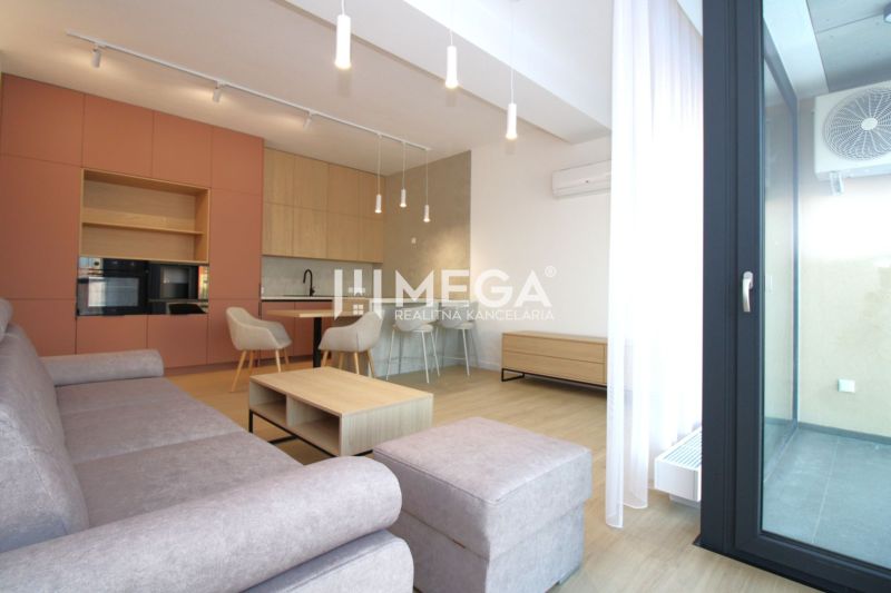 Living room of a three-room apartment with a wooden decor floor and a modern kitchen unit.