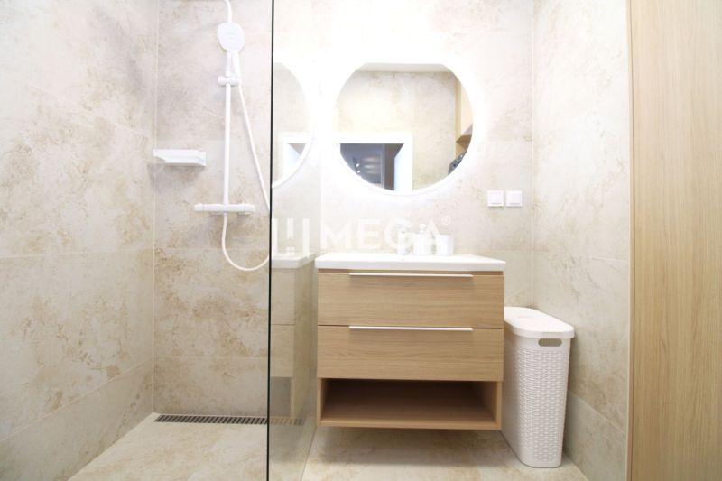 A bathroom with a shower and wooden decor in a 3-room apartment.