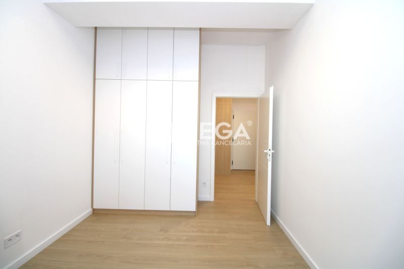 A room in a three-room apartment with a white built-in wardrobe and a floor with a wooden decor.