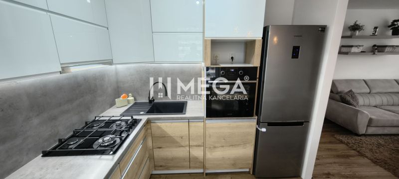 A kitchen with white cabinets, gray tiles, and appliances in a 3-room apartment.